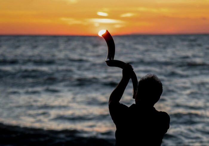 Person blowing Shofar Horn